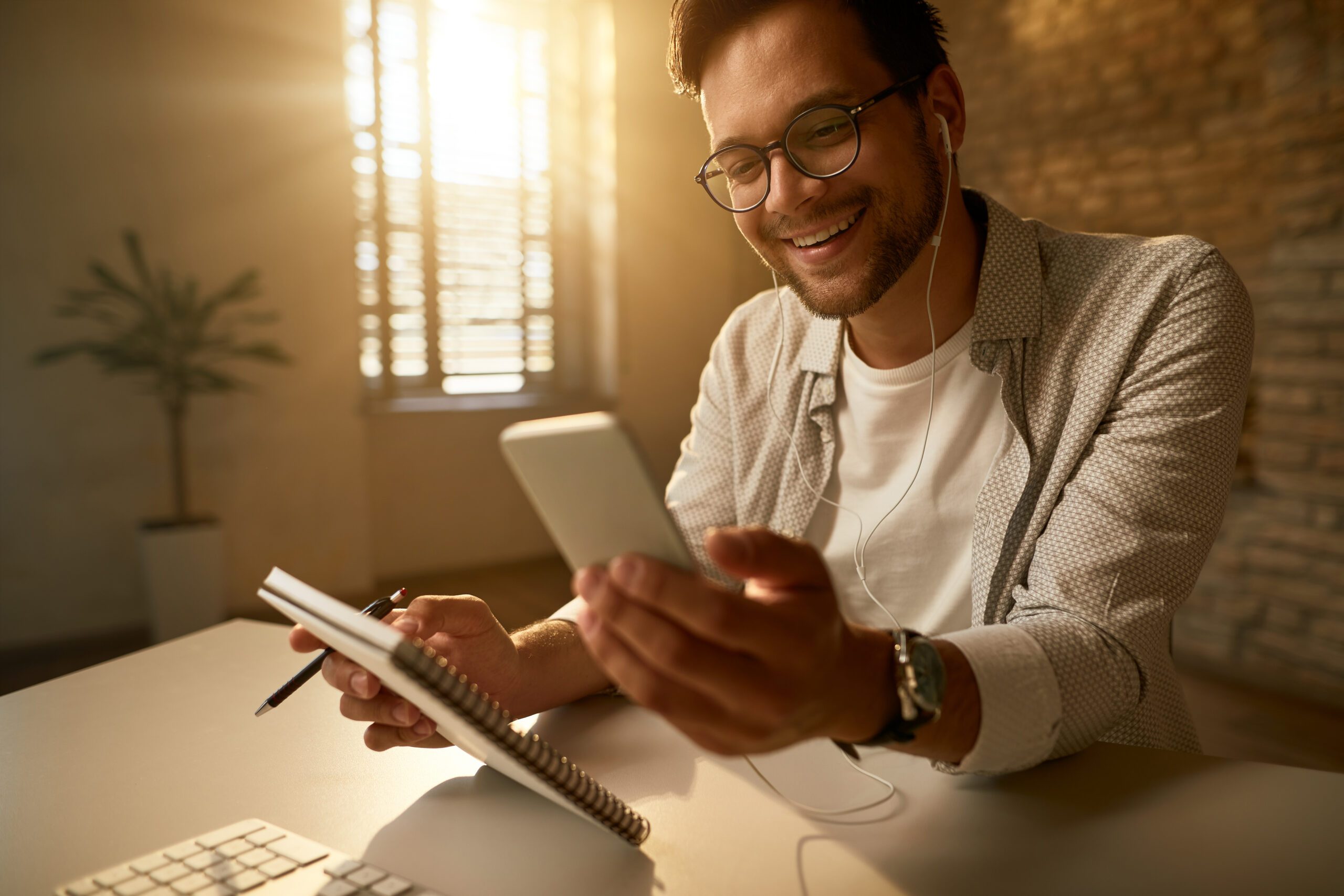 young-happy-freelance-worker-using-mobile-phone-reading-text-message-while-working-office-scaled.jpg